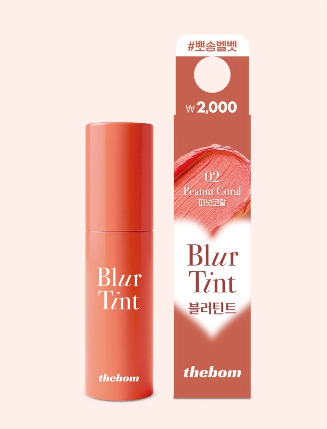 A product photograph of a 'thebom Blur Tint' lip product, specifically shade '02 Peanut Coral', next to its cardboard packaging. Both the coral-colored tube and the coral packaging feature the text 'Blur Tint' and 'thebom'. The packaging also includes Korean text, the number '02 Peanut Coral', a swatch of the color, and a price tag of '₩ 2,000'