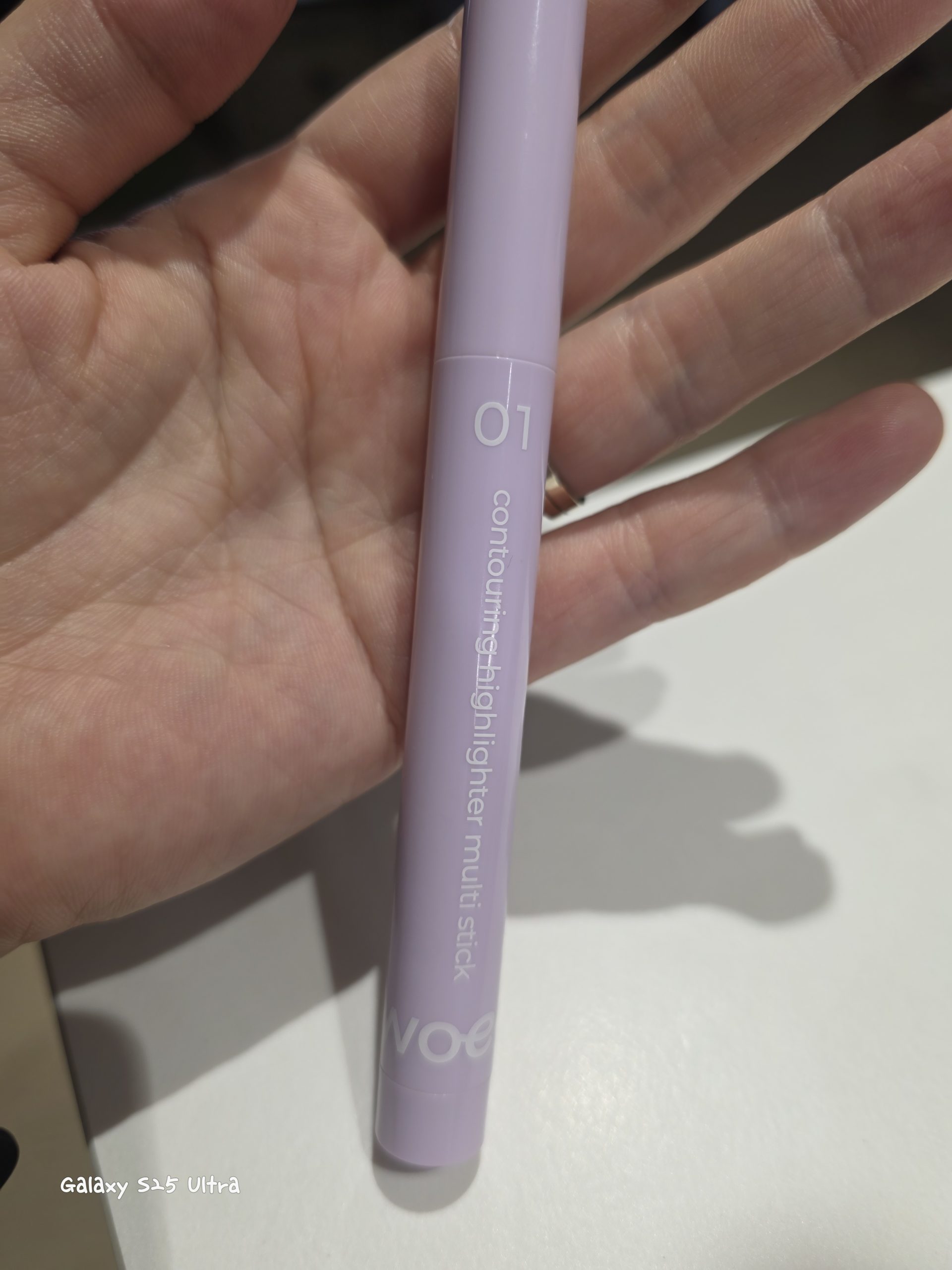 Hand holding a pastel purple Son & Park contouring highlighter multi stick 01