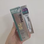 Hand holding a box of VT PDRN Glow Cream for elasticity and wrinkle care in front of a white wall