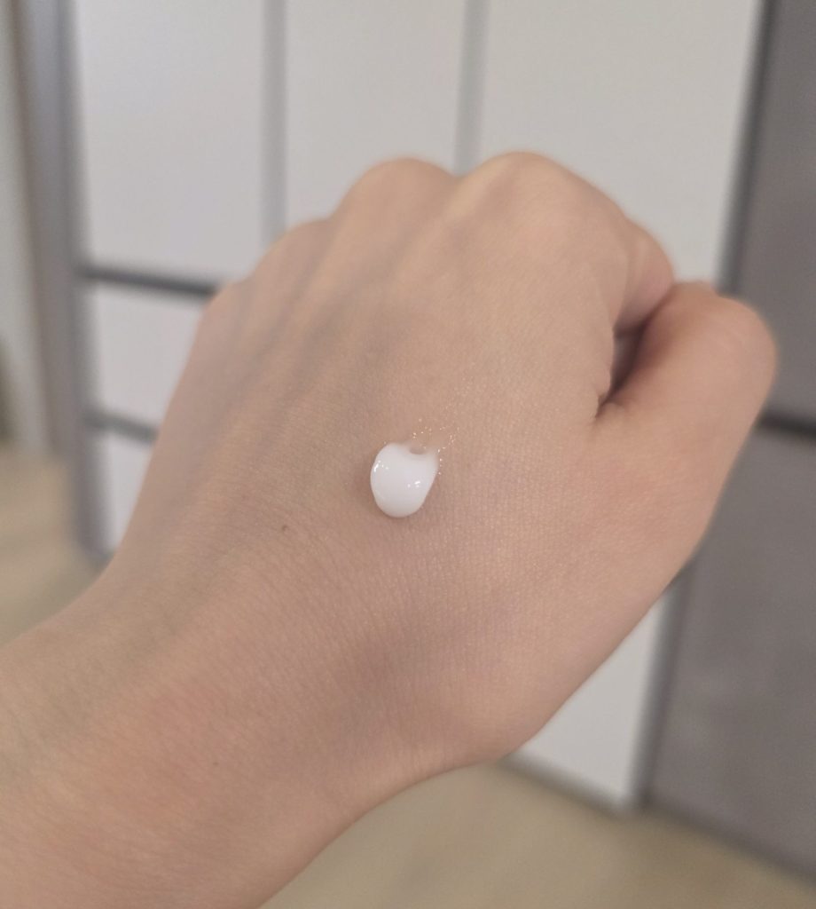 A pea-sized amount of white facial cream tested on the back of a hand.