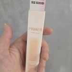 Hand holding a box of Klavuu Pore Balm Primer for smooth skin texture.