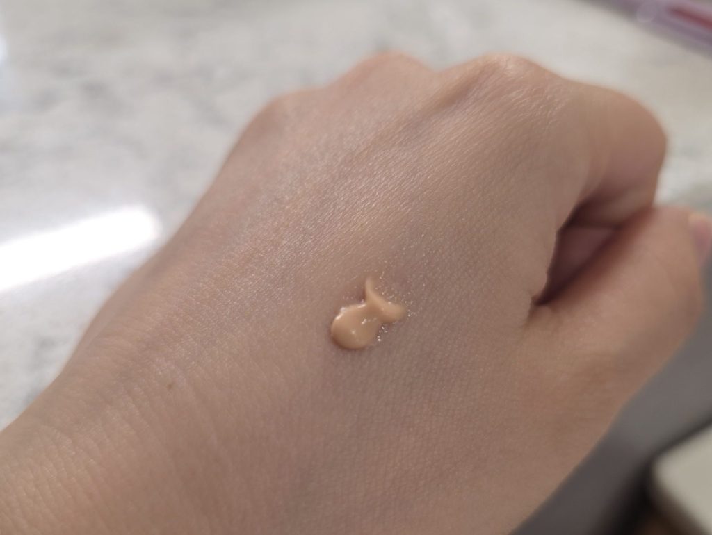 Light beige cosmetic primer texture swatch tested on the back of a hand.